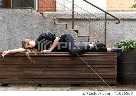 The girl is lying on the bench. The girl is lying on the bench. 41086567