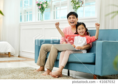 Dad spending holiday on laptop with living room sofa with daughter 41087032