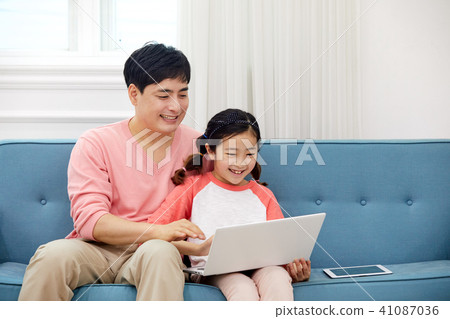 Dad spending holiday on laptop with living room sofa with daughter 41087036