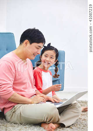 爸爸度假在筆記本電腦上與客廳沙發與女兒 爸爸度假在筆記本電腦上與客廳沙發與女兒 41087219