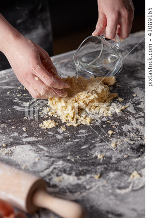 On a kitchen table the women's hands kneads the dough. Step-by-step preparation of the dough 41089165