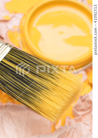 Paintbrush and can lid  with yellow paint, closeup 41092313