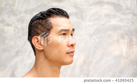 Asian men dye his hair color on a gray background. Asian men dye his hair color on a gray background. 41093425