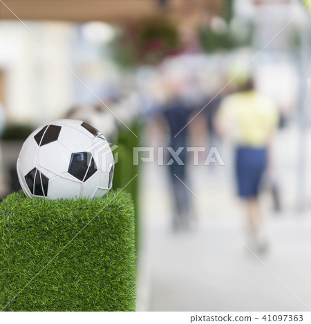 Decorative stand in the form of the classic football ball in the net on the green grass. Ornaments 41097363