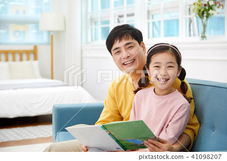 A happy picture of a dad reading a book from his living room sofa and having a holiday, reading 41098207