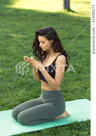 Fitness girl with a smartphone on nature background Fitness girl with a smartphone on nature background 41098271