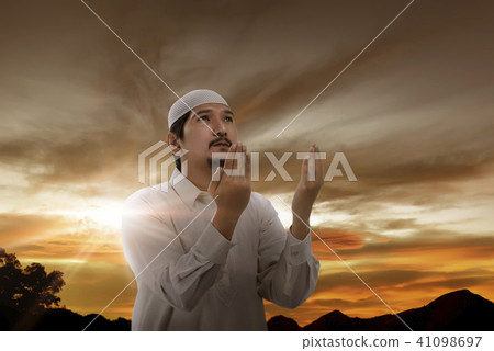 Handsone asian muslim man raising hand and pray Handsone asian muslim man raising hand and pray 41098697