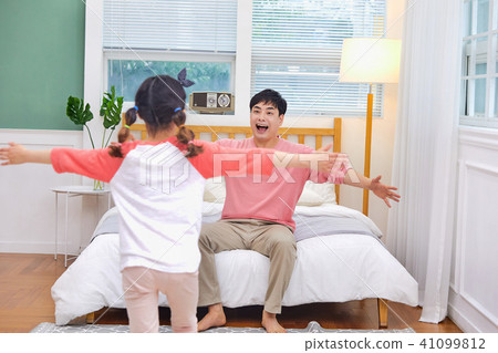 A loving daughter runs to her father in bed and hugs him 41099812