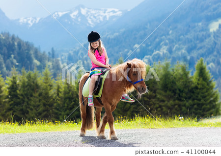 Kids riding pony. Child on horse in Alps mountains Kids riding pony. Child on horse in Alps mountains 41100044
