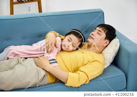 Adorable daughter sleeping in her dad's arms on the sofa Adorable daughter sleeping in her dad's arms on the sofa 41100238