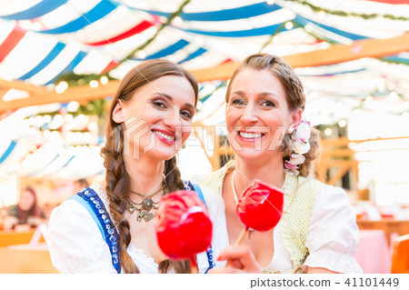 Friends in a beer tent holding candy apples 41101449
