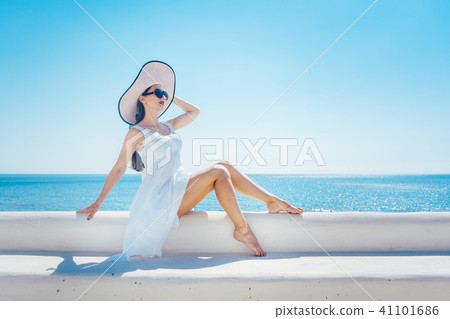 Woman sitting in the sun on a greek beach Woman sitting in the sun on a greek beach 41101686