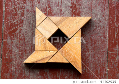 Tangram puzzle in shuriken shape on red old wood Tangram puzzle in shuriken shape on red old wood 41102935