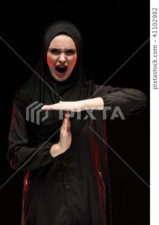 Portrait of beautiful desperate scared frightened young muslim woman wearing black hijab showing 41102982