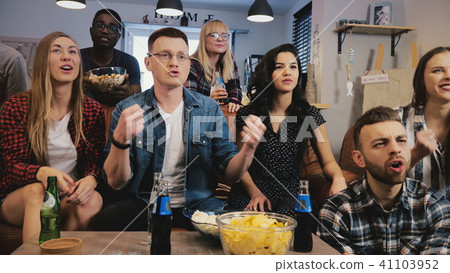Multi ethnic supporters watching sports on TV. 4K slow motion. Sports fans cheer together for Multi ethnic supporters watching sports on TV. 4K slow motion. Sports fans cheer together for 41103952