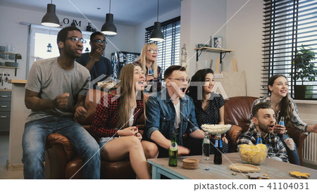Multi-ethnic happy sports fans celebrate goal. 4K slow motion. African American friends support 41104031