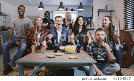 Mixed race friends watch sports on TV. Student football fans supporters get upset. Cheering for Mixed race friends watch sports on TV. Student football fans supporters get upset. Cheering for 41104067