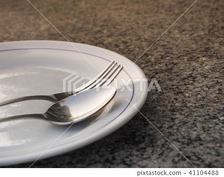Silver spoon placed on a white plate 41104488