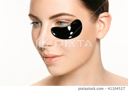 Young beautiful woman applying a mask for the face of the therapeutic black mud. Spa treatment 41104527