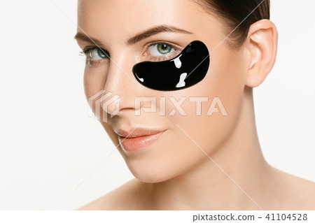 Young beautiful woman applying a mask for the face of the therapeutic black mud. Spa treatment 41104528