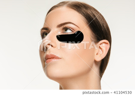 Young beautiful woman applying a mask for the face of the therapeutic black mud. Spa treatment Young beautiful woman applying a mask for the face of the therapeutic black mud. Spa treatment 41104530