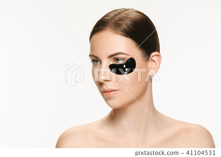 Young beautiful woman applying a mask for the face of the therapeutic black mud. Spa treatment 41104531