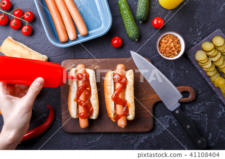 Picture on top of table with ingredients for hot dogs, cutting board, man's hands Picture on top of table with ingredients for hot dogs, cutting board, man's hands 41108404