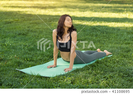 Woman practicing yoga outdoors in park Woman practicing yoga outdoors in park 41108695