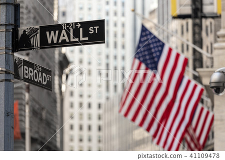 Wall street sign in New York with American flags and New York Stock Exchange background. Wall street sign in New York with American flags and New York Stock Exchange background. 41109478