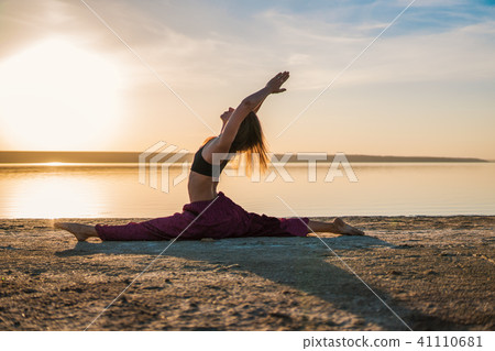 Silhouette yoga woman on the beach at sunset. 41110681