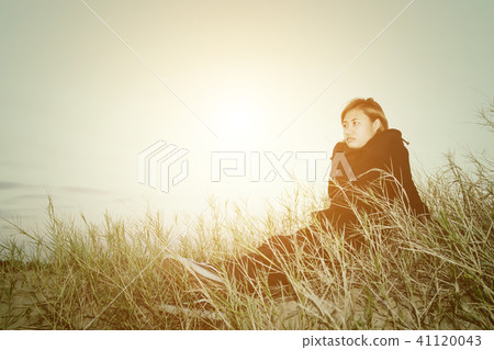 Sad young woman sitting on the grass feeling Sad young woman sitting on the grass feeling 41120043