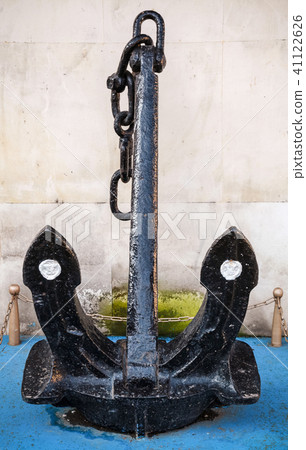Big black anchor stands near wall in port 41122626