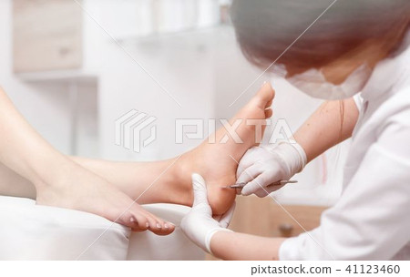 Profeesional doctor polish callus and corn on feet of client. Profeesional doctor polish callus and corn on feet of client. 41123460