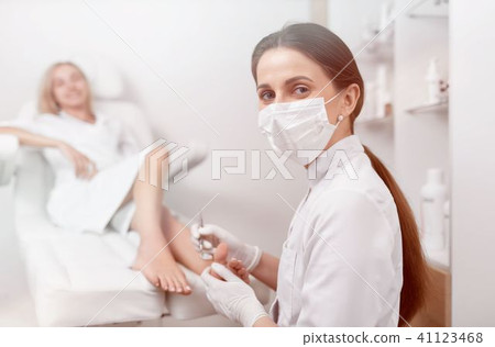 Podiatrist in mask on face looking at camera and working. Podiatrist in mask on face looking at camera and working. 41123468