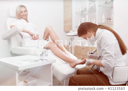 Podiatrist making procedure for smiling clients foot. Podiatrist making procedure for smiling clients foot. 41123583