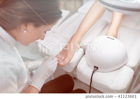 Specialist in beauty salon cleaning cuticle around nails on feet Specialist in beauty salon cleaning cuticle around nails on feet 41123601