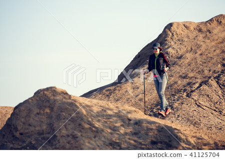 Photo in full growth of tourist girl with backpack and sticks for walking on mountain 41125704