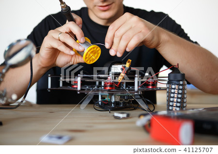 Photo of engineer with soldering iron repairing mechanism 41125707