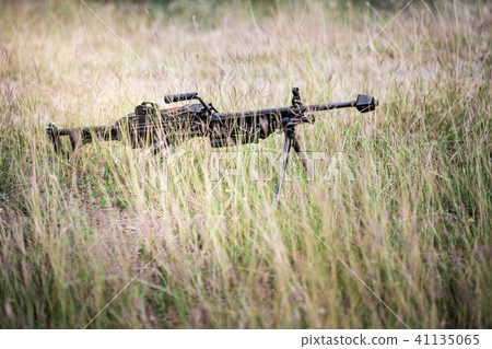 Machine gun on tripod and hidden at field grass. Machine gun on tripod and hidden at field grass. 41135065