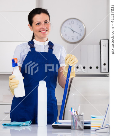 Cheerful female cleaning furniture in office Cheerful female cleaning furniture in office 41137832