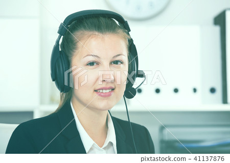 Portrait of dispatcher female in black suit which is talking by headset with client 41137876