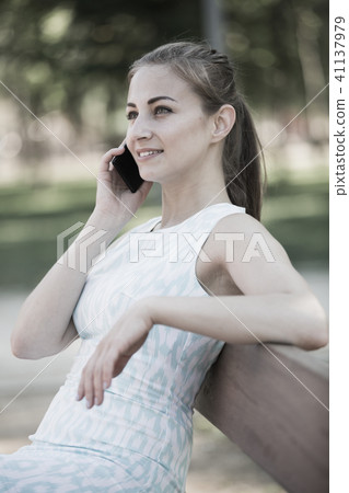 girl sitting on a bench and using telephone in outdoor girl sitting on a bench and using telephone in outdoor 41137979