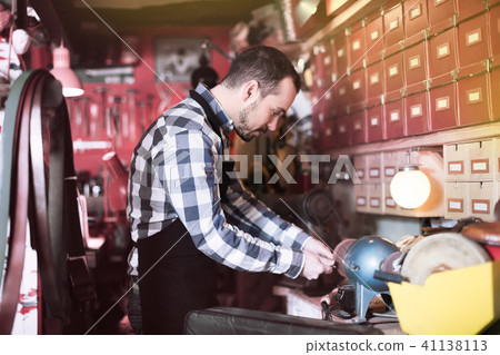 Young man worker working on belt buckle Young man worker working on belt buckle 41138113