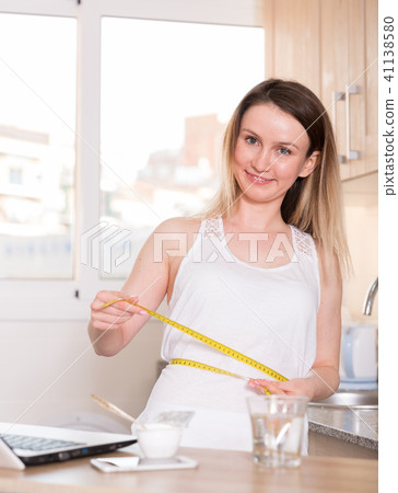 Portrait of sporty female who is standing and measuring waist Portrait of sporty female who is standing and measuring waist 41138580