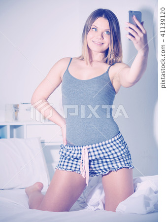 Teenage girl smiling in camera and making selfie in bed 41139120