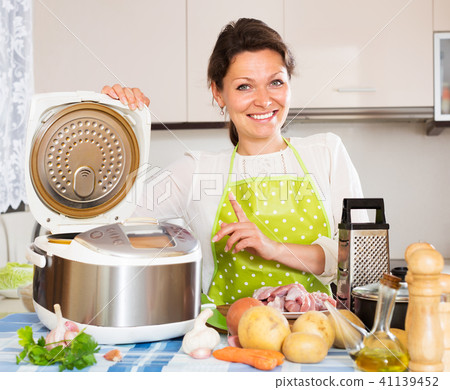 Happy woman using slo-cooker Happy woman using slo-cooker 41139452