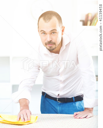 Positive young man cleaning office desk Positive young man cleaning office desk 41139458