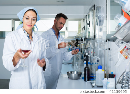 Woman winery expert in white coat checking quality of wine Woman winery expert in white coat checking quality of wine 41139695