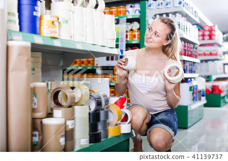 happy woman customer choosing adhesive tape in household store 41139737
