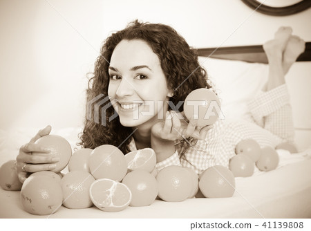 Positive girl eating oranges in bed Positive girl eating oranges in bed 41139808